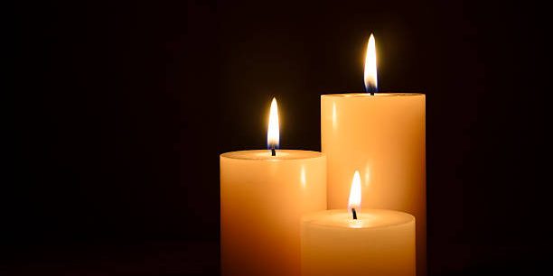 Three lit candles isolated on a black background.